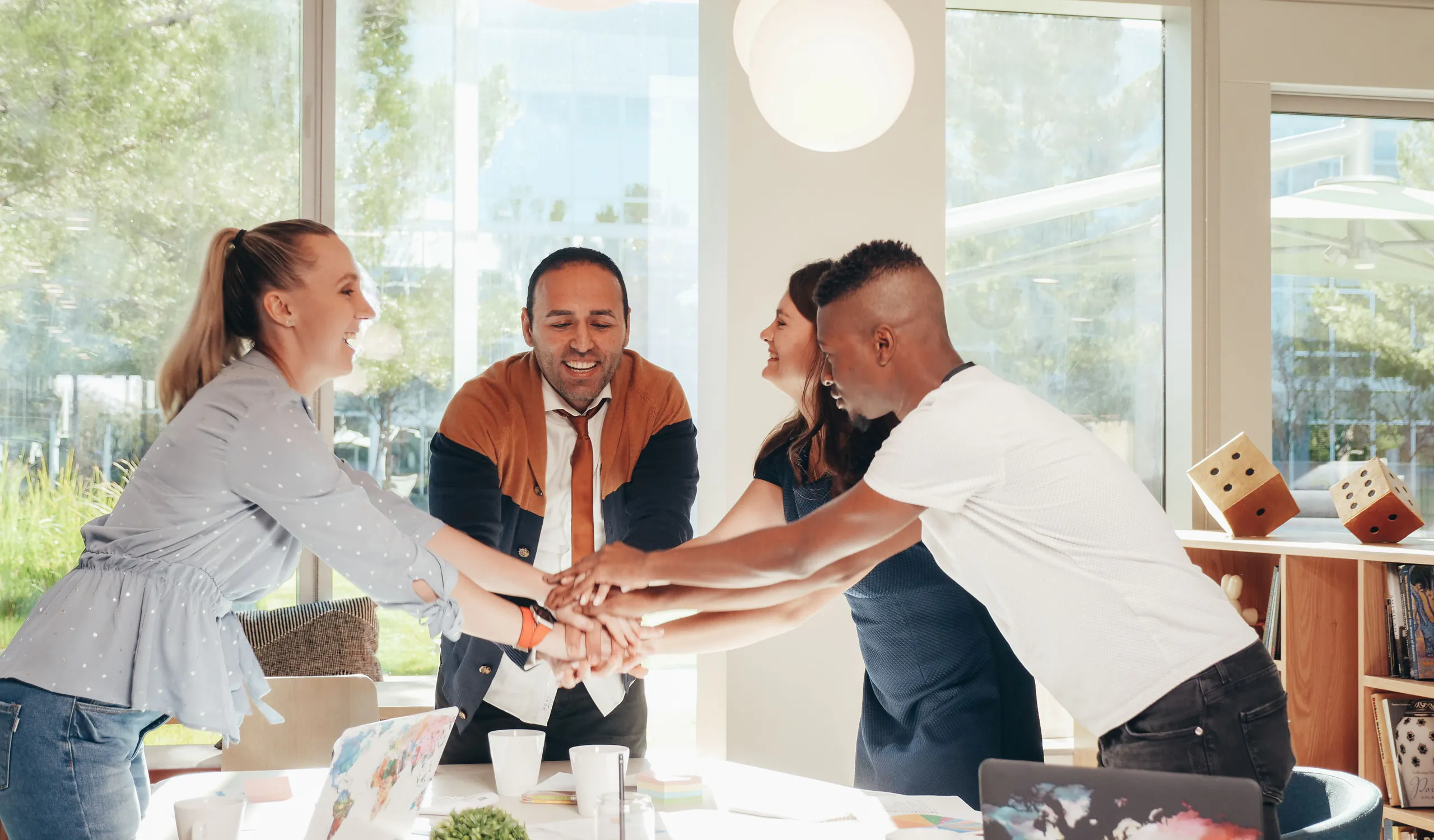 A diverse team joining hands around a project table